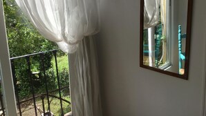 A room with a large window, a balcony with a metal railing, and a view of greenery outside. - Pensión San José (Granada)