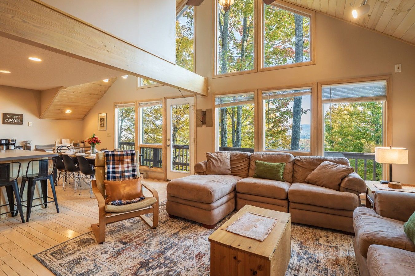 A spacious living area with a large window, a dining area, and a kitchen.