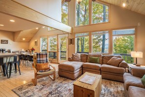 A spacious living area with a large window, a dining area, and a kitchen.