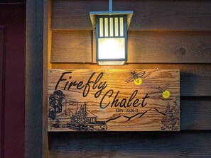 Een houten bord met de tekst 'Firefly Chalet' en een hoogte van 1075 meter.