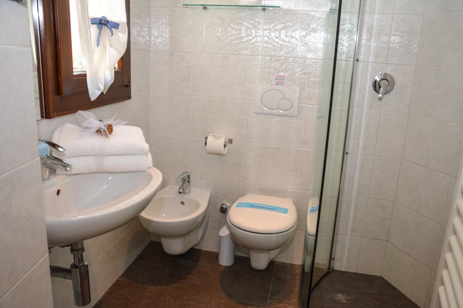 A bathroom with a sink, bidet, toilet, and glass shower enclosure.