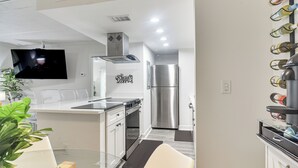 Een moderne keuken met een roestvrijstalen koelkast, een flatscreen televisie aan de muur en een wijnrek aan de rechterkant.