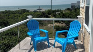 Un pontile in legno con due poltrone Adirondack blu rivolte verso la vista dell'oceano.