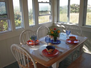 A dining table with chairs, a vase with flowers, and various dishes and glasses.