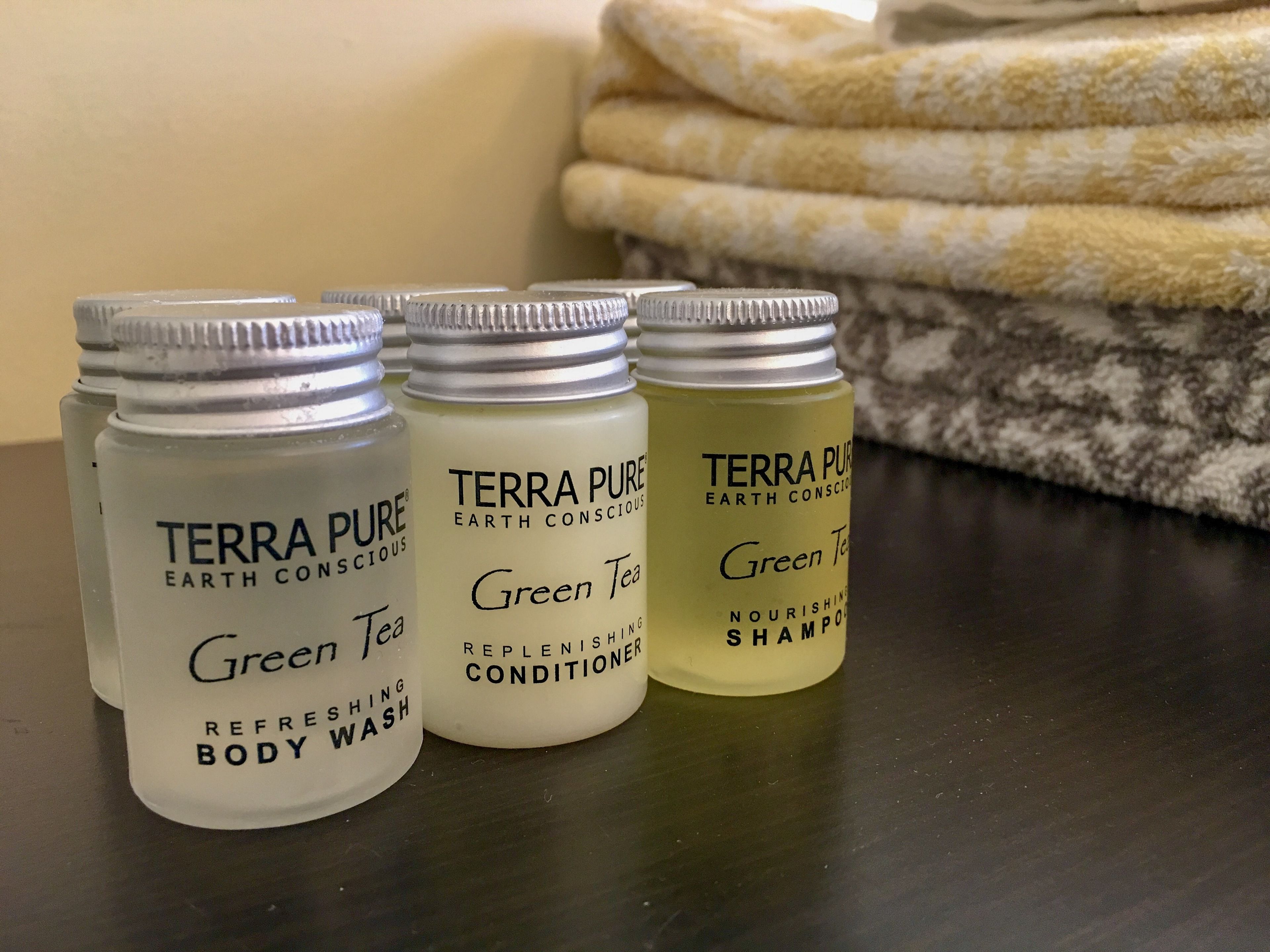 Quatre produits de la gamme Terra Pure : gel douche rafraîchissant, après-shampoing au thé vert, shampoing au thé vert et shampoing nourrissant.