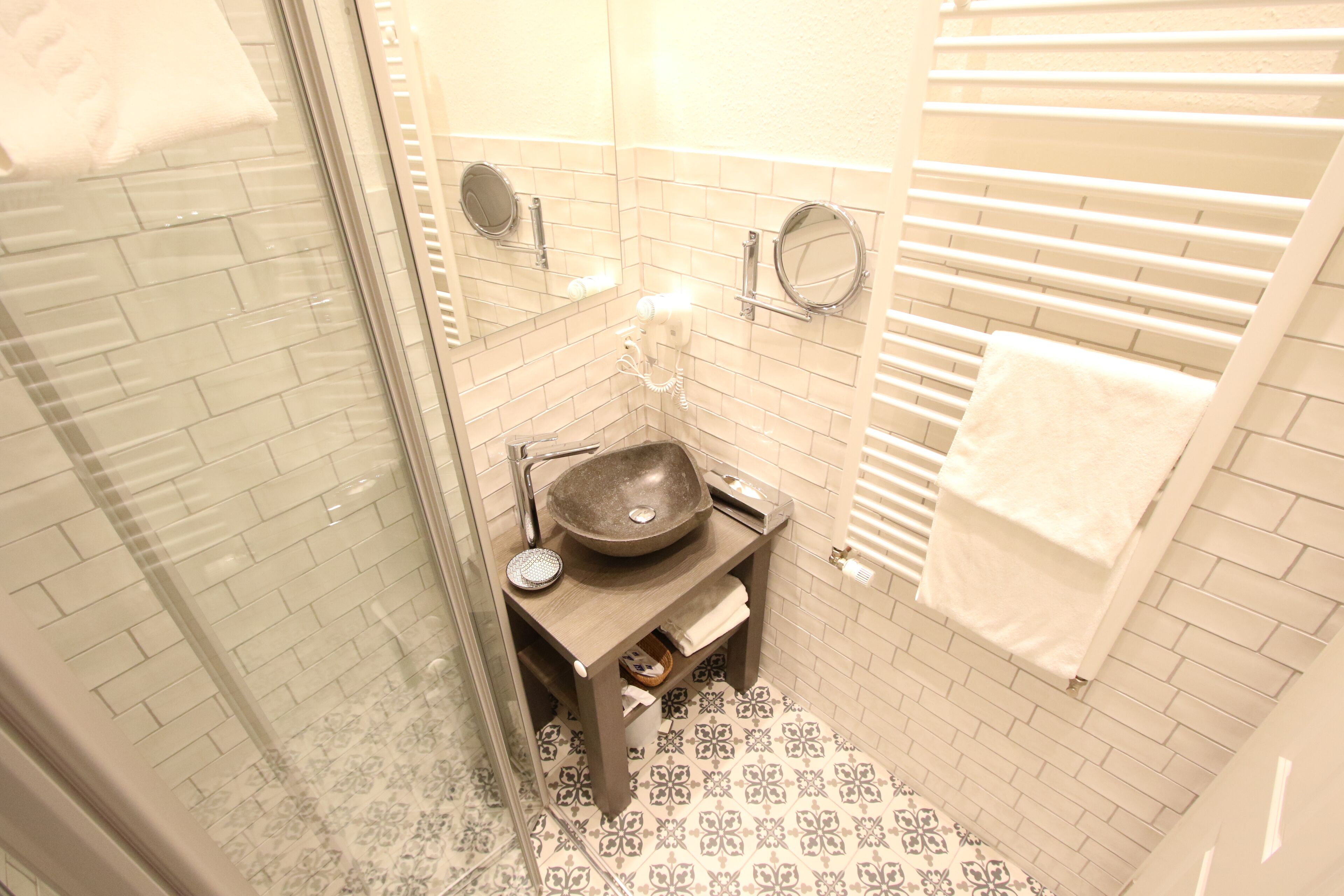 A small bathroom with a glass shower enclosure, a sink with a vessel basin, and a towel rack.