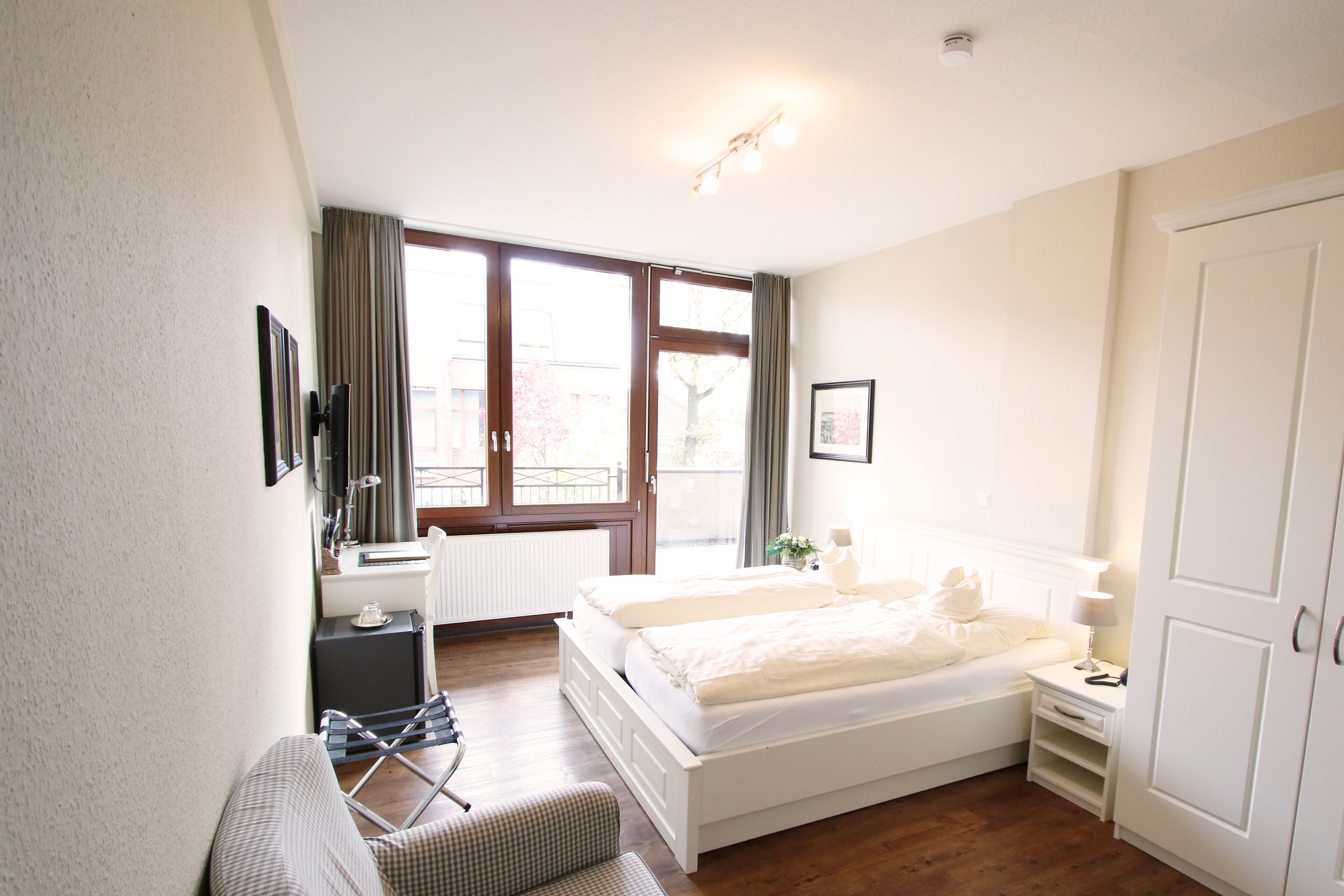 A bedroom with a bed, a desk, a chair, and a window with curtains.
