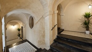 Una imponente escalera con piso estampado que lleva a una habitación con un amplio arco.