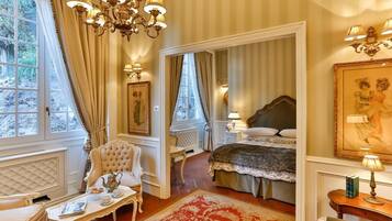 Una habitación con una cama grande, una zona de estar con una silla y una mesa, y vistas al exterior a través de una ventana.
