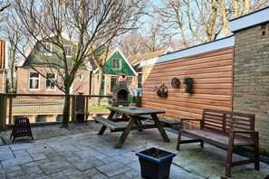 Relax and socialize in this inviting patio area, featuring a picnic table, bench, and chair, as well as an outdoor cooking facility.