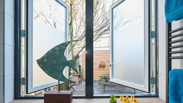 A room with a large window, a decorative metal sculpture, and a few rubber ducks on the windowsill.