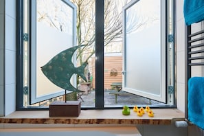 Enter a spacious area with a large doorway leading to an outdoor space, flanked by glass panels and a striking metal sculpture.