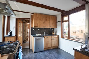 Efficient cooking and cleaning facilities are provided by a stove and compact dishwasher, complemented by cabinetry and a window with a view of the backyard.