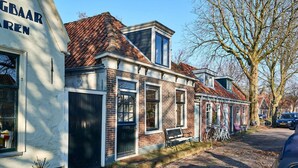 A row of traditional brick buildings with a cobblestone street, a bench, and bicycles parked outside.