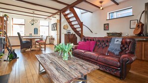 A spacious living room with a wooden coffee table, a leather sofa, and a staircase.