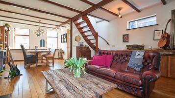 A spacious living room with a wooden coffee table, a leather sofa, and a staircase.