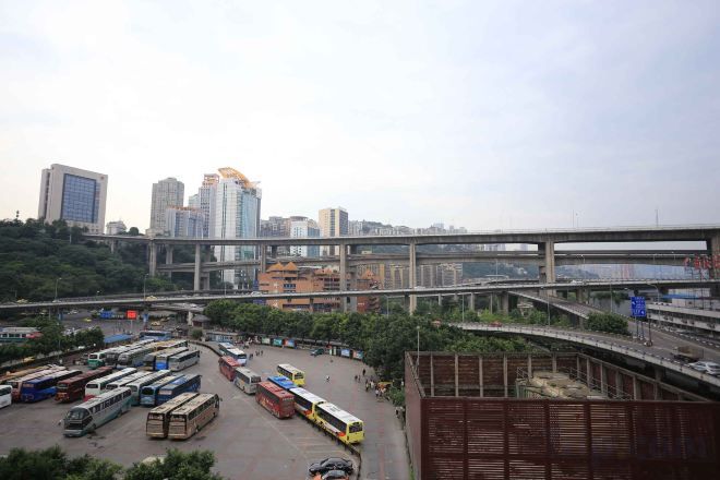 A bus station with multiple buses and a pedestrian overpass.