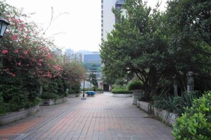 A paved pathway flanked by greenery and a tall building in the background. - Chongqing Fujiayuan Hotel (Lianglukou Subway Station) (Chongqing)