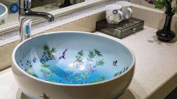 A bathroom with a large, round, blue ceramic sink with plant designs.