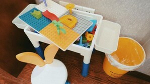 Une petite table avec un lapin en peluche, une voiture jouet et un ensemble de cuisine miniature.