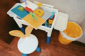Une petite table avec un lapin en peluche, une voiture jouet et un ensemble de cuisine miniature.