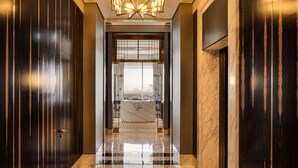 Un moderno vestíbulo de hotel con mostrador de recepción de mármol, paneles de madera oscura y una gran araña.