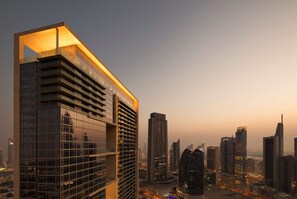 A modern high-rise building with multiple floors and a distinctive architectural design, surrounded by other tall buildings in a cityscape.