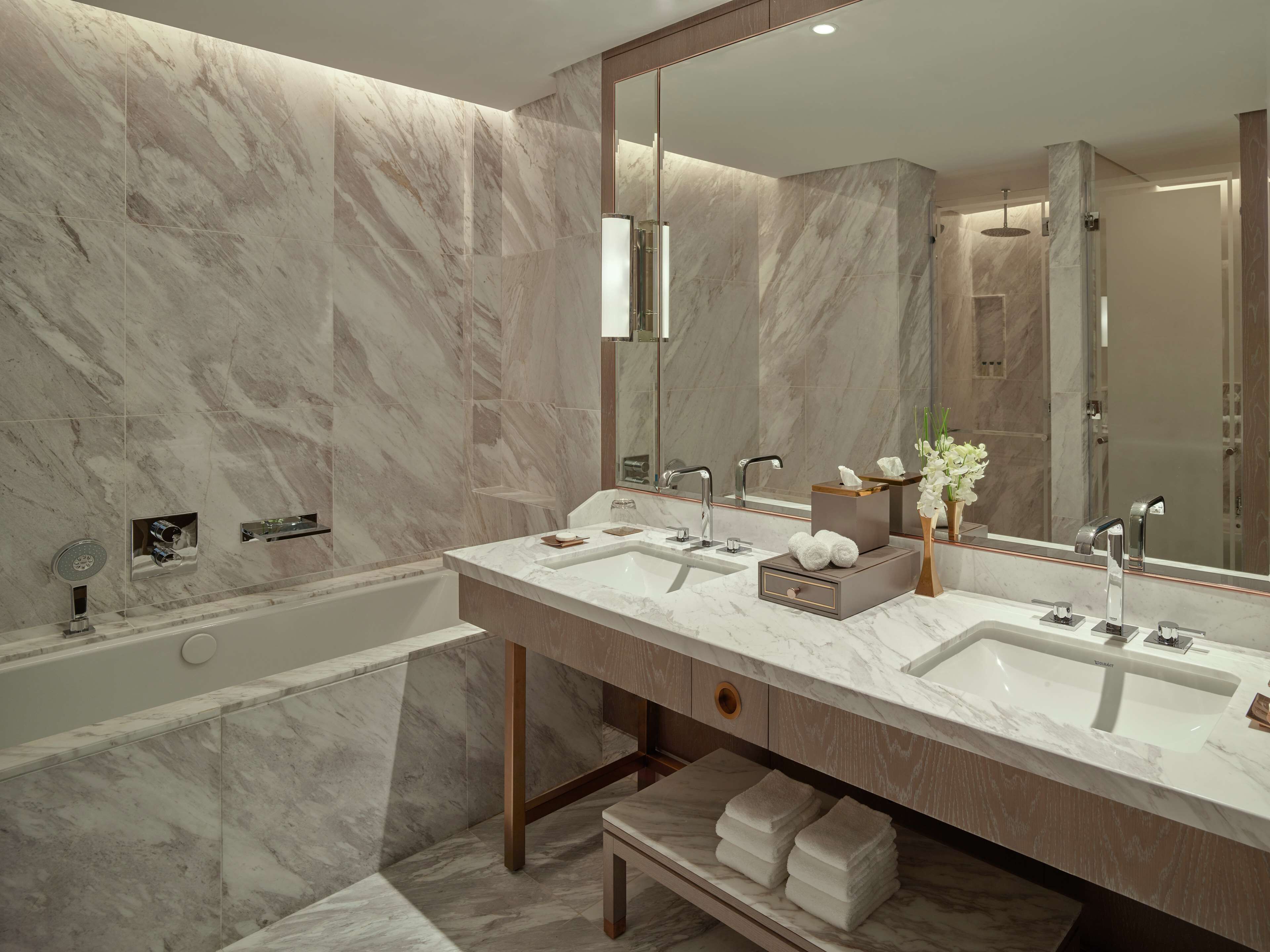 A modern bathroom with marble walls and two sinks.