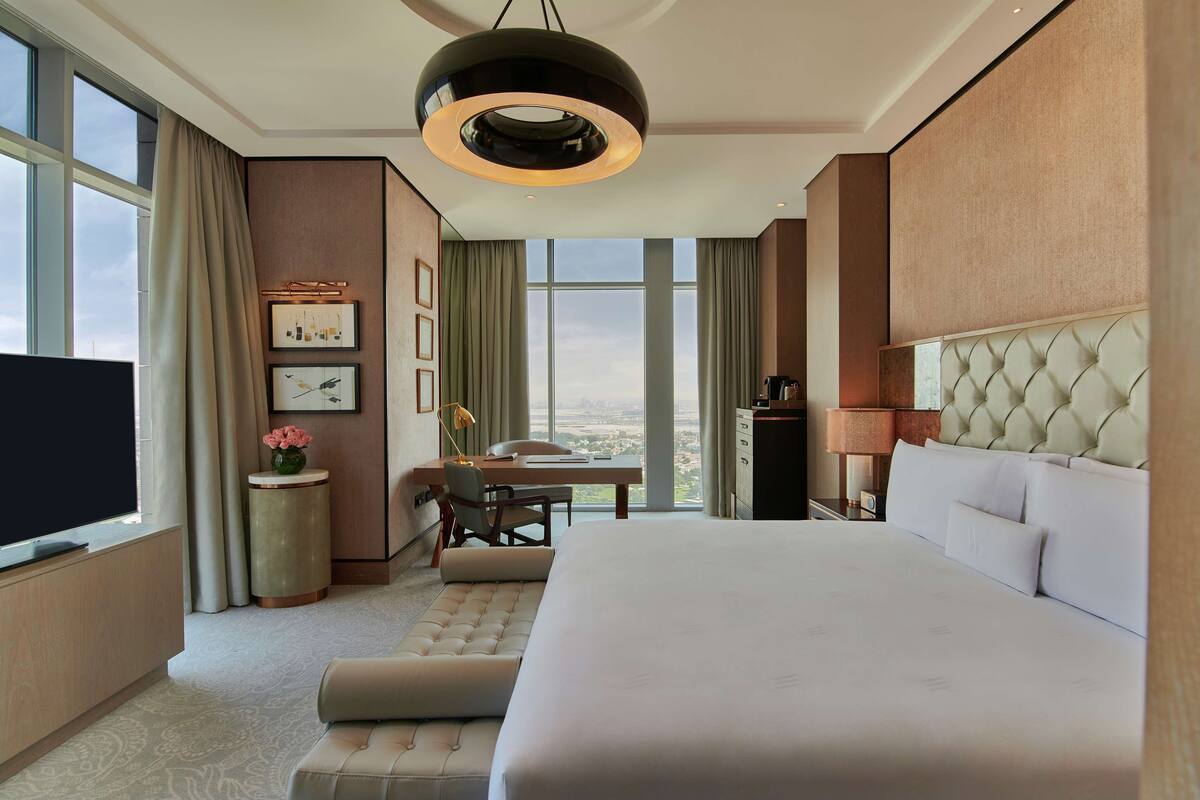 A modern hotel room with a large bed, a desk, and a television.