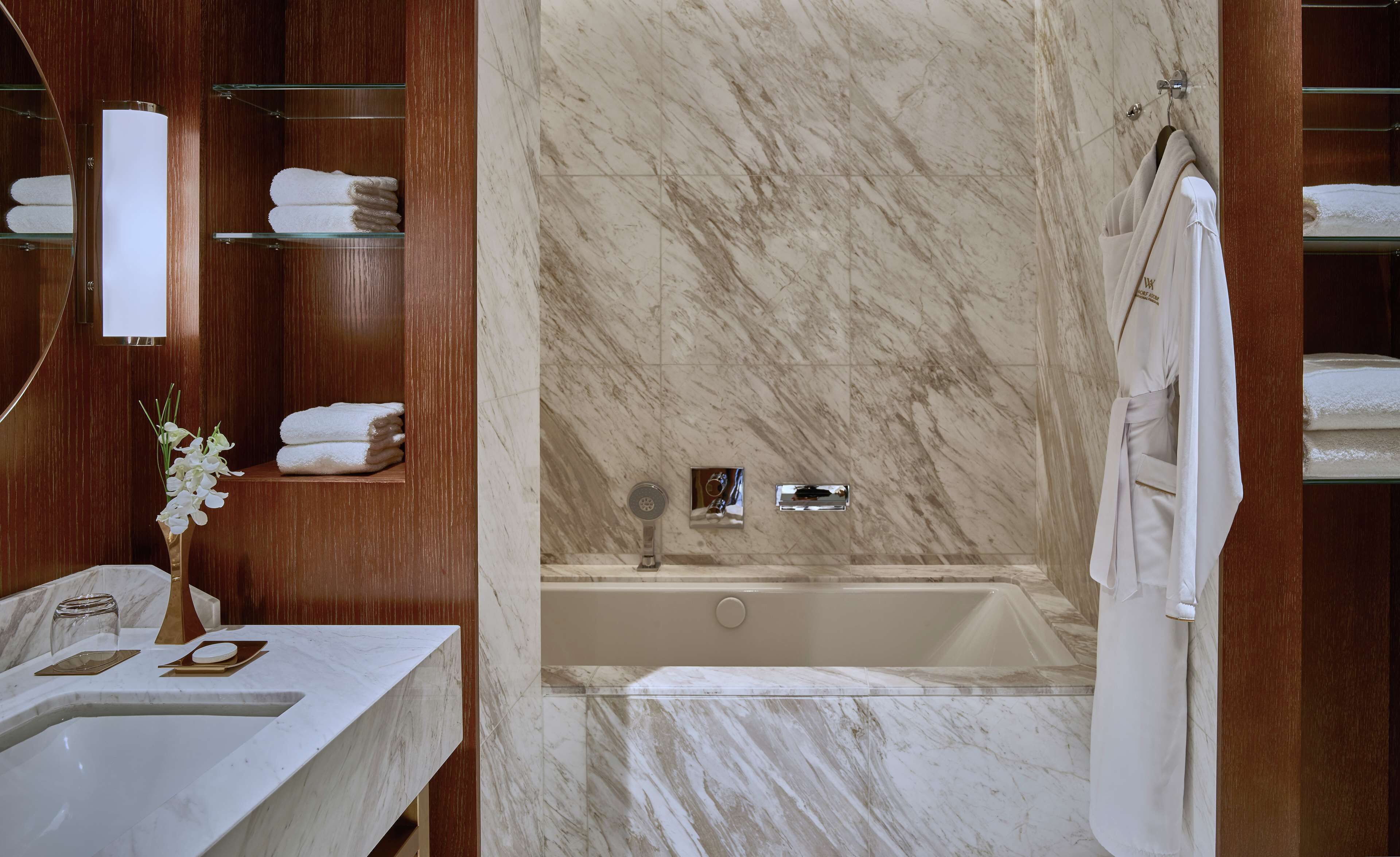 A modern bathroom with a marble sink, a bathtub, and a glass shower enclosure.
