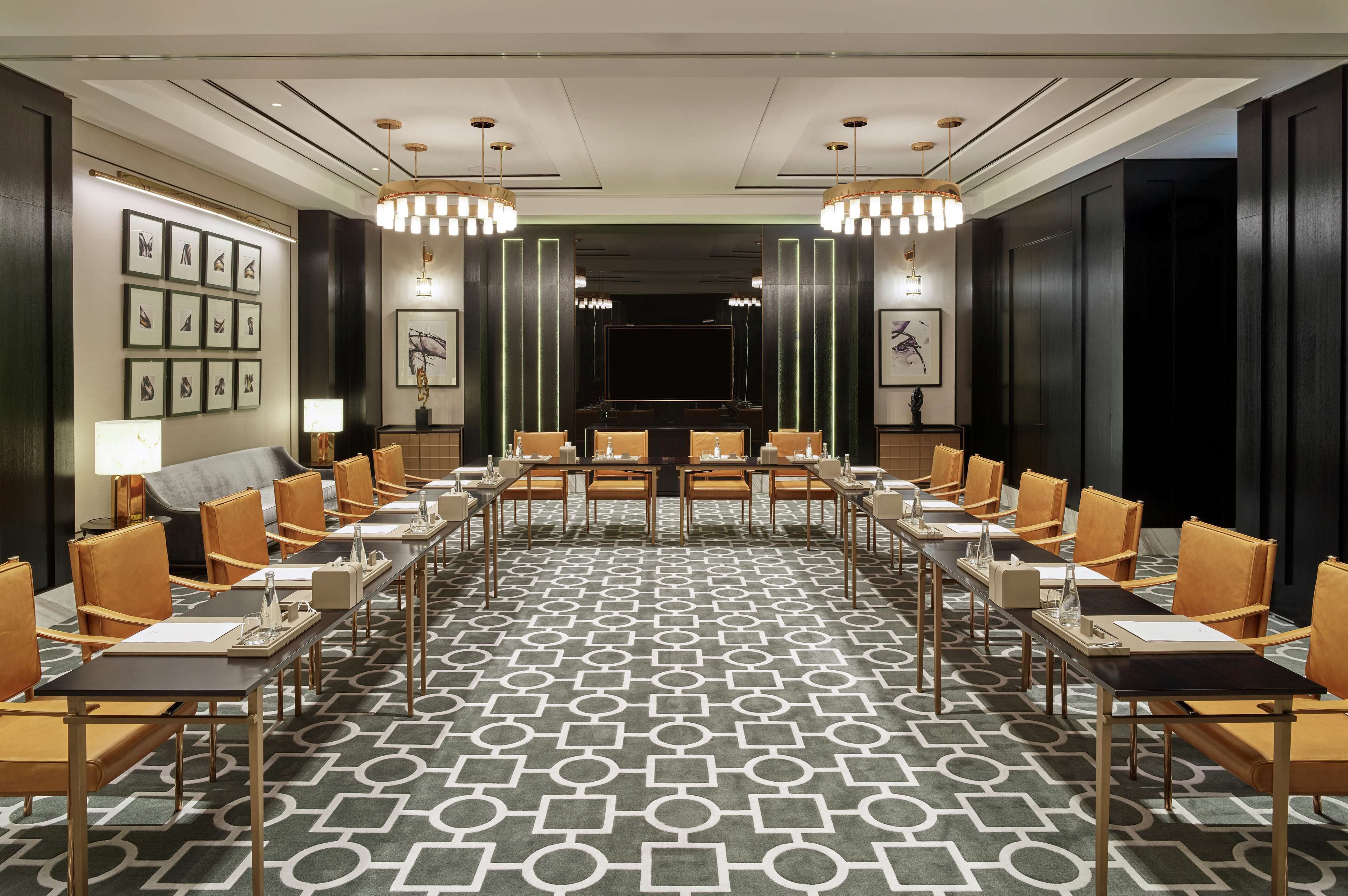 A conference room with a long table, chairs, and a patterned carpet.