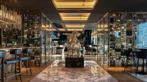 A modern bar with a central sculpture, glass display cases, and seating areas. - Waldorf Astoria Dubai International Financial Centre (Dubai)