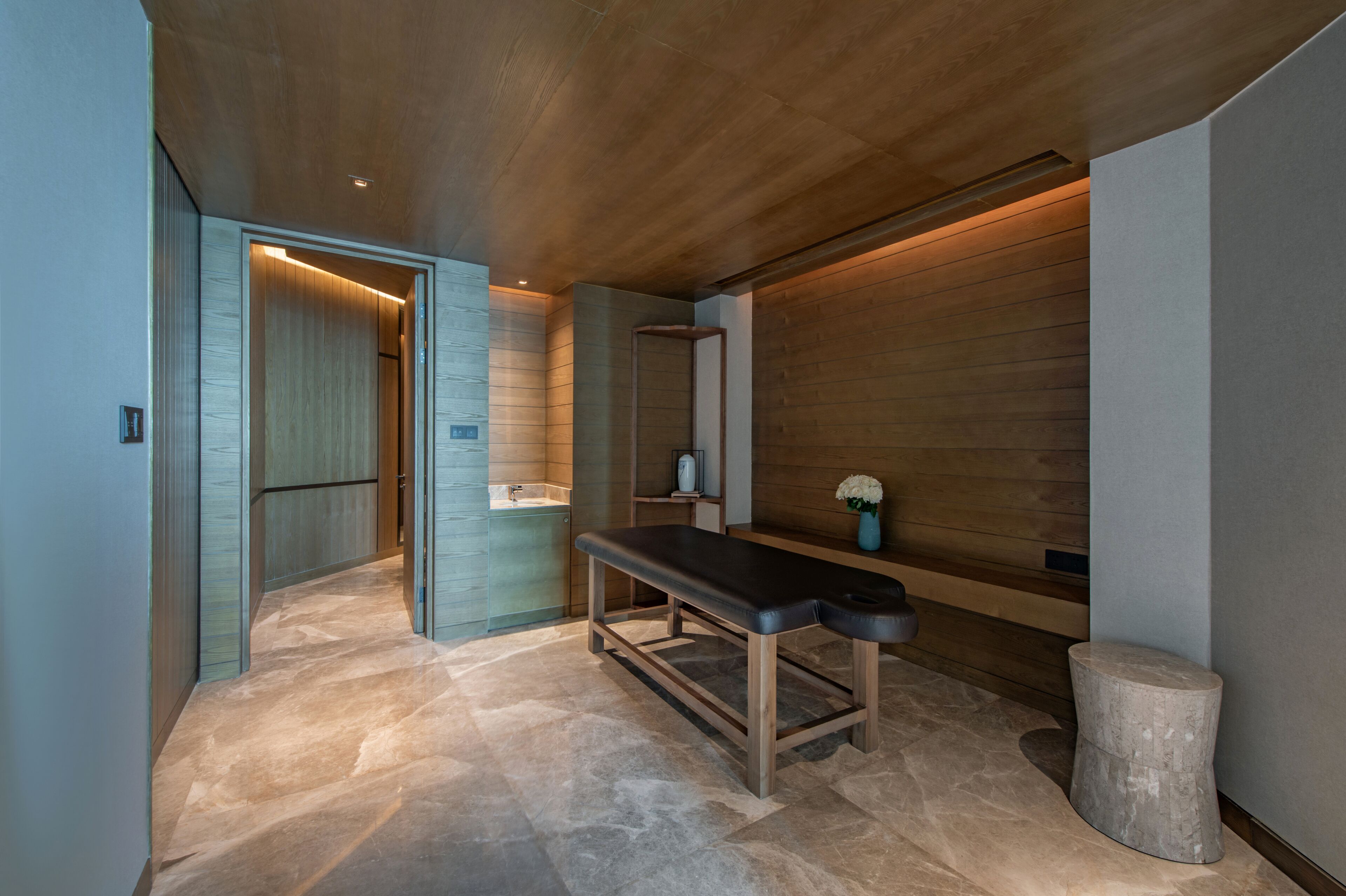 A modern bathroom with a bench, a small sink, and wooden paneling.