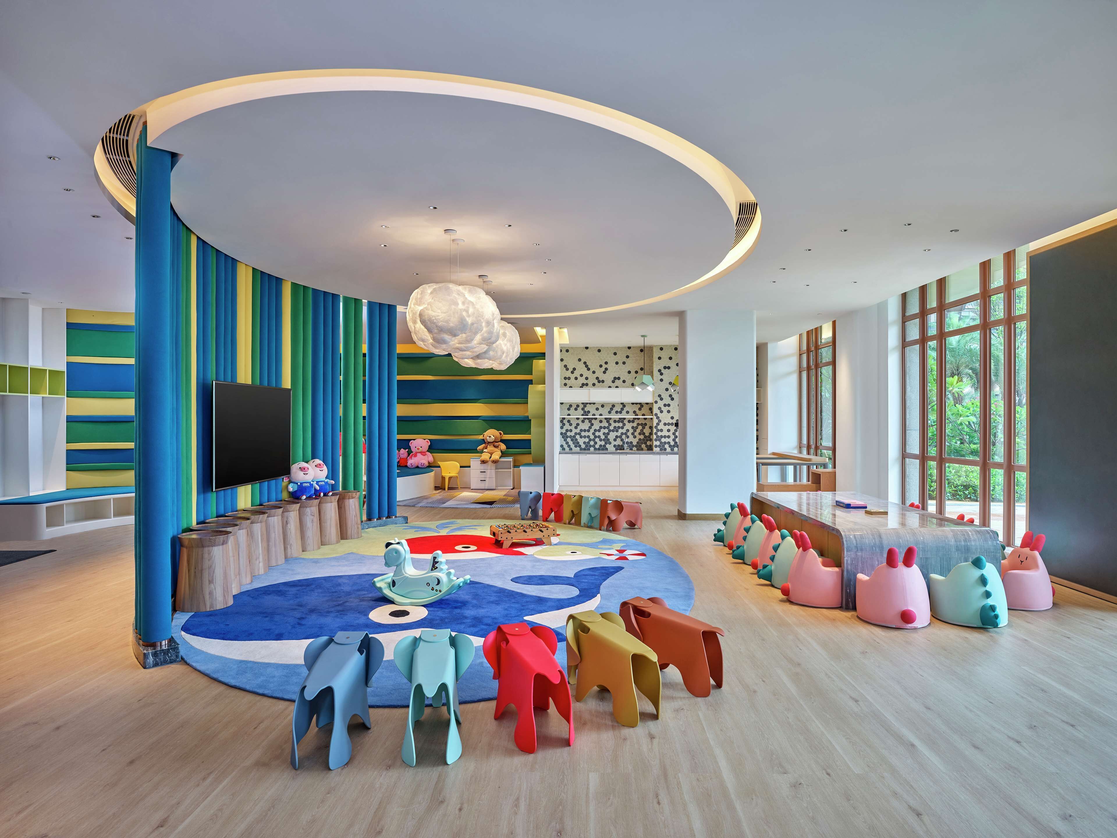 Una sala de juegos infantil moderna con muebles coloridos y un techo grande y curvo.