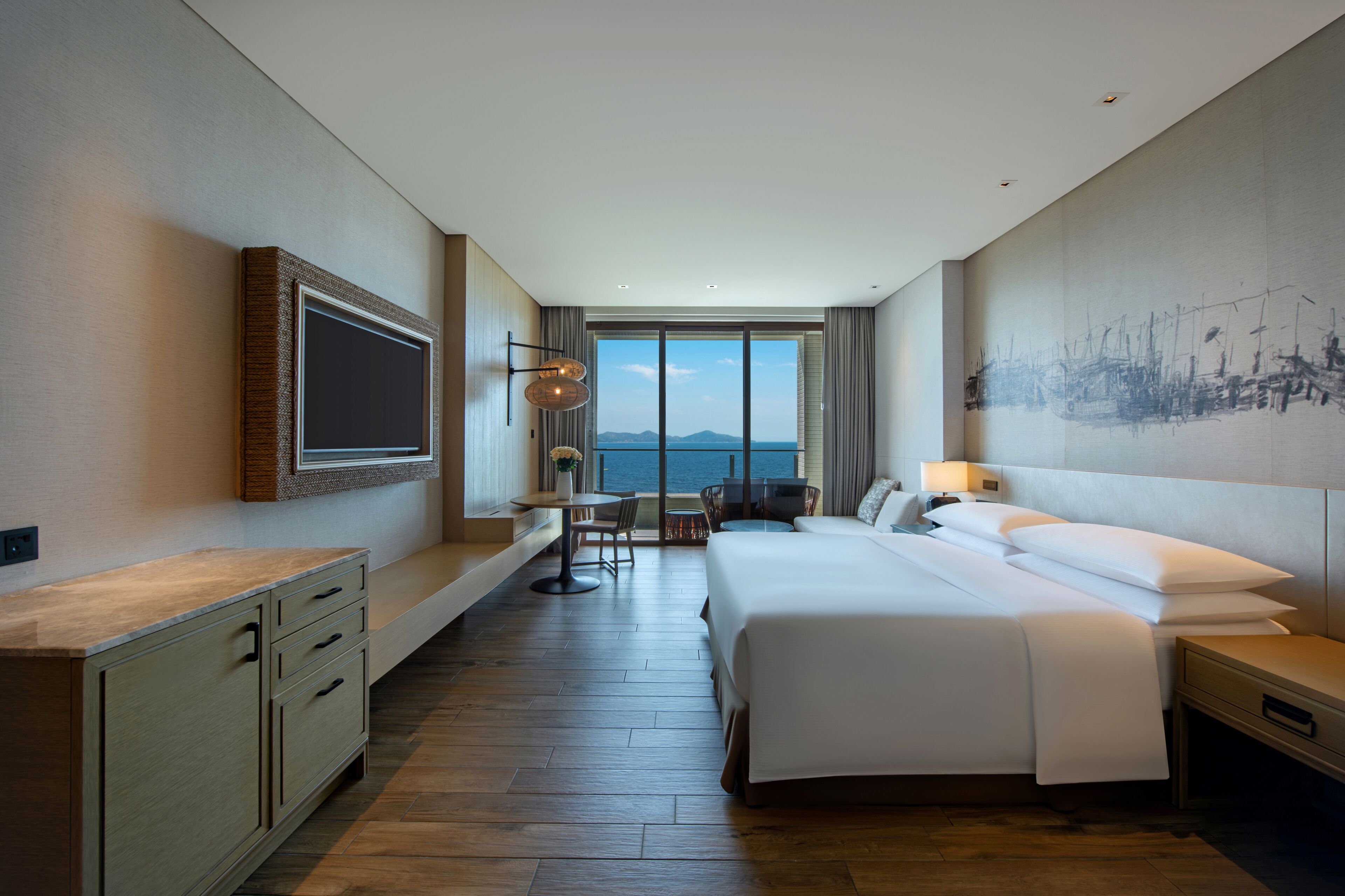 Une chambre d’hôtel moderne avec un grand lit, un bureau et une vue sur la mer.