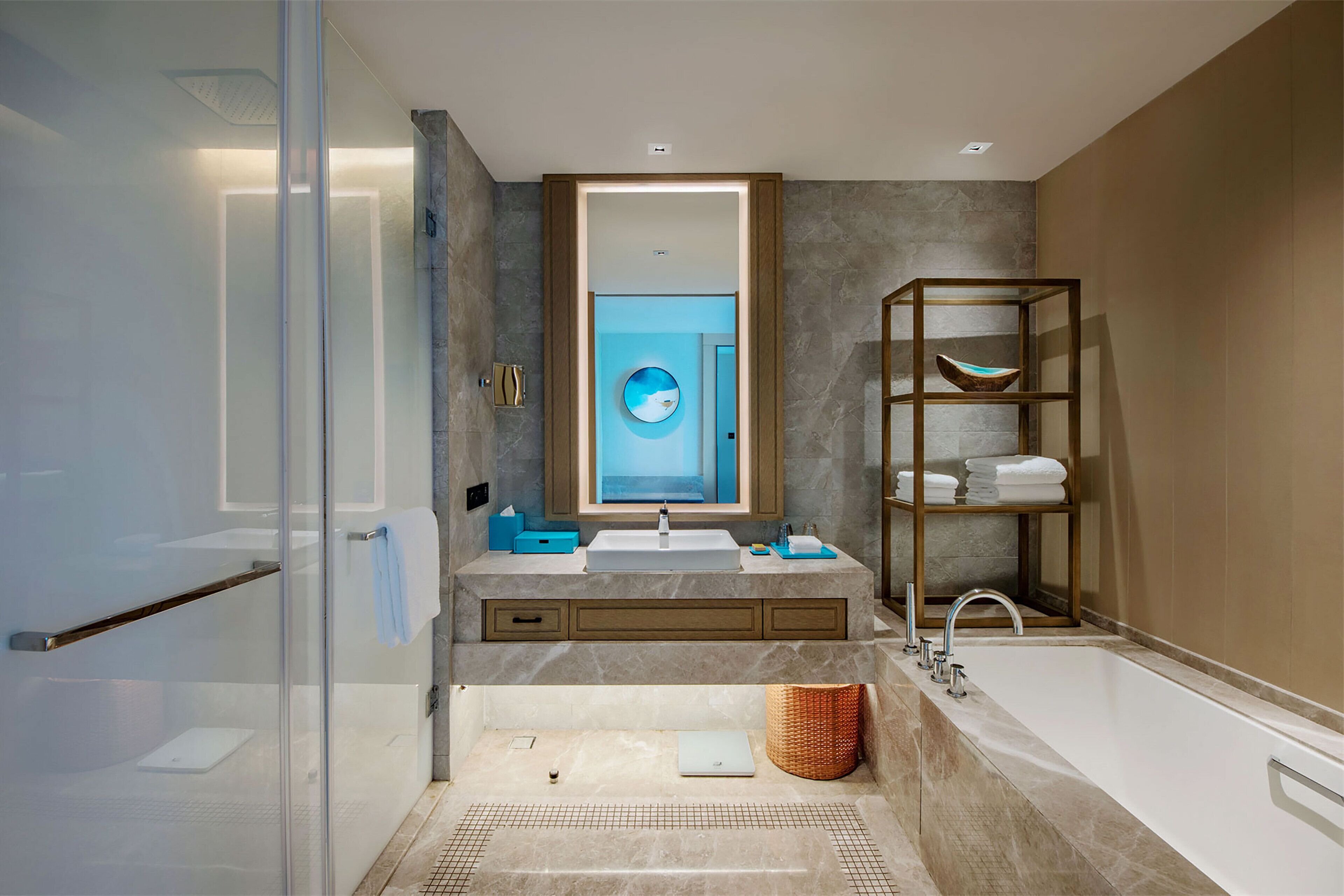Ein modernes Badezimmer mit Duschkabine aus Glas, einer großzügigen Badewanne, einem Waschtisch mit Spüle und Spiegel sowie einem Ablagebereich mit Handtüchern.