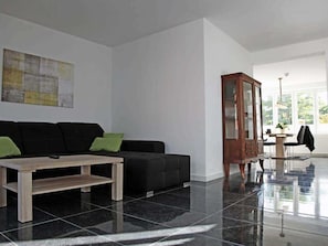 A modern living room with a black sofa, a wooden coffee table, and a large cabinet.