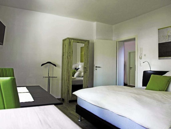 Une chambre d’hôtel avec un lit, un bureau, une chaise et une armoire.