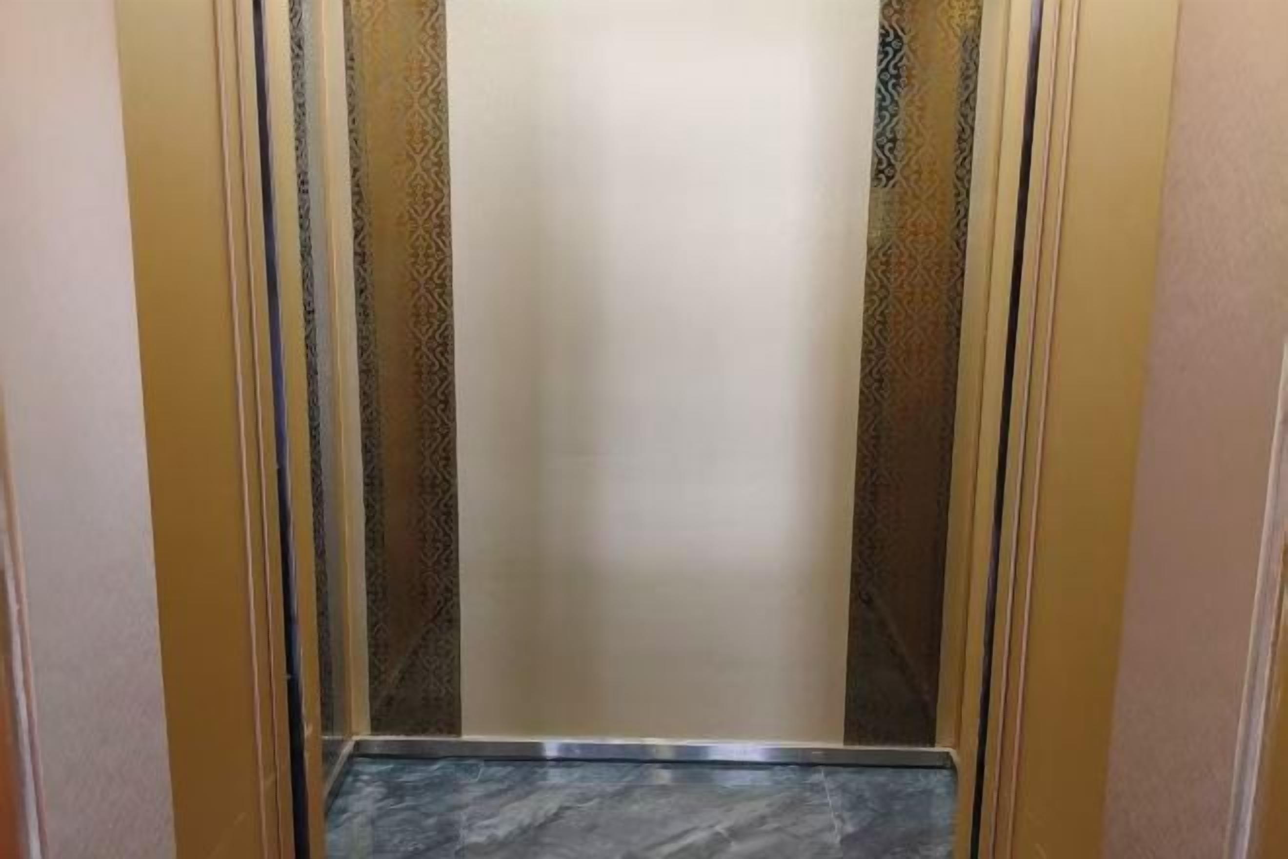 An elevator interior with a marble floor and patterned walls.