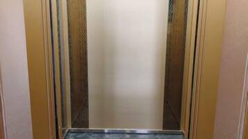 An elevator interior with a marble floor and patterned walls.