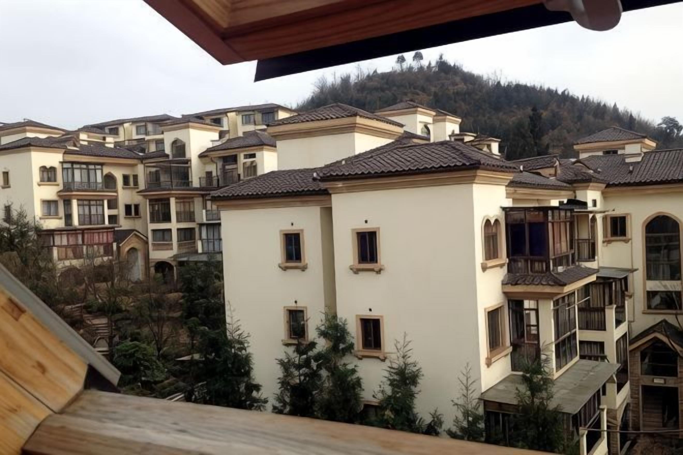 A residential area with multiple two-story buildings, balconies, and a hilly background.