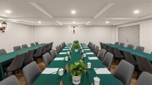 A conference room with long tables, chairs, and potted plants. - Taimei Holiday Hotel (Chongqing)