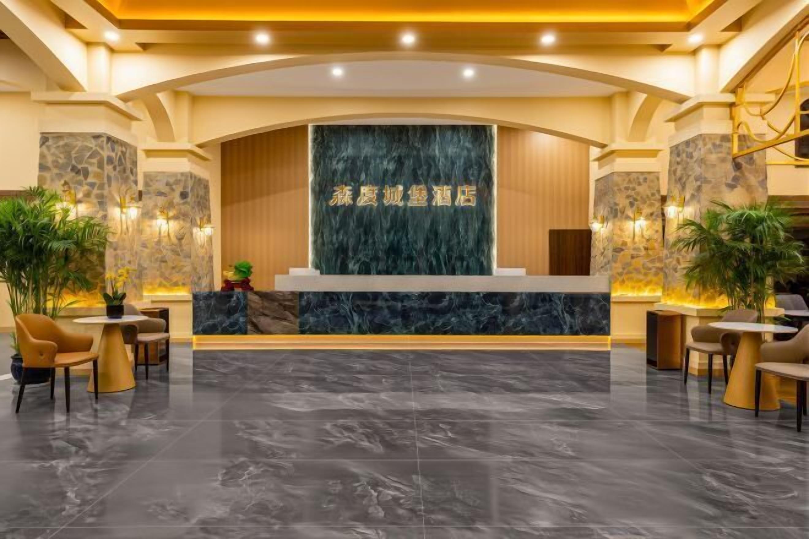 Zona de recepción de un hotel con mostrador de mármol, asientos y plantas.