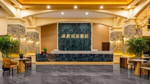 A hotel reception area with a marble counter, seating, and plants. - Taimei Holiday Hotel (Chongqing)