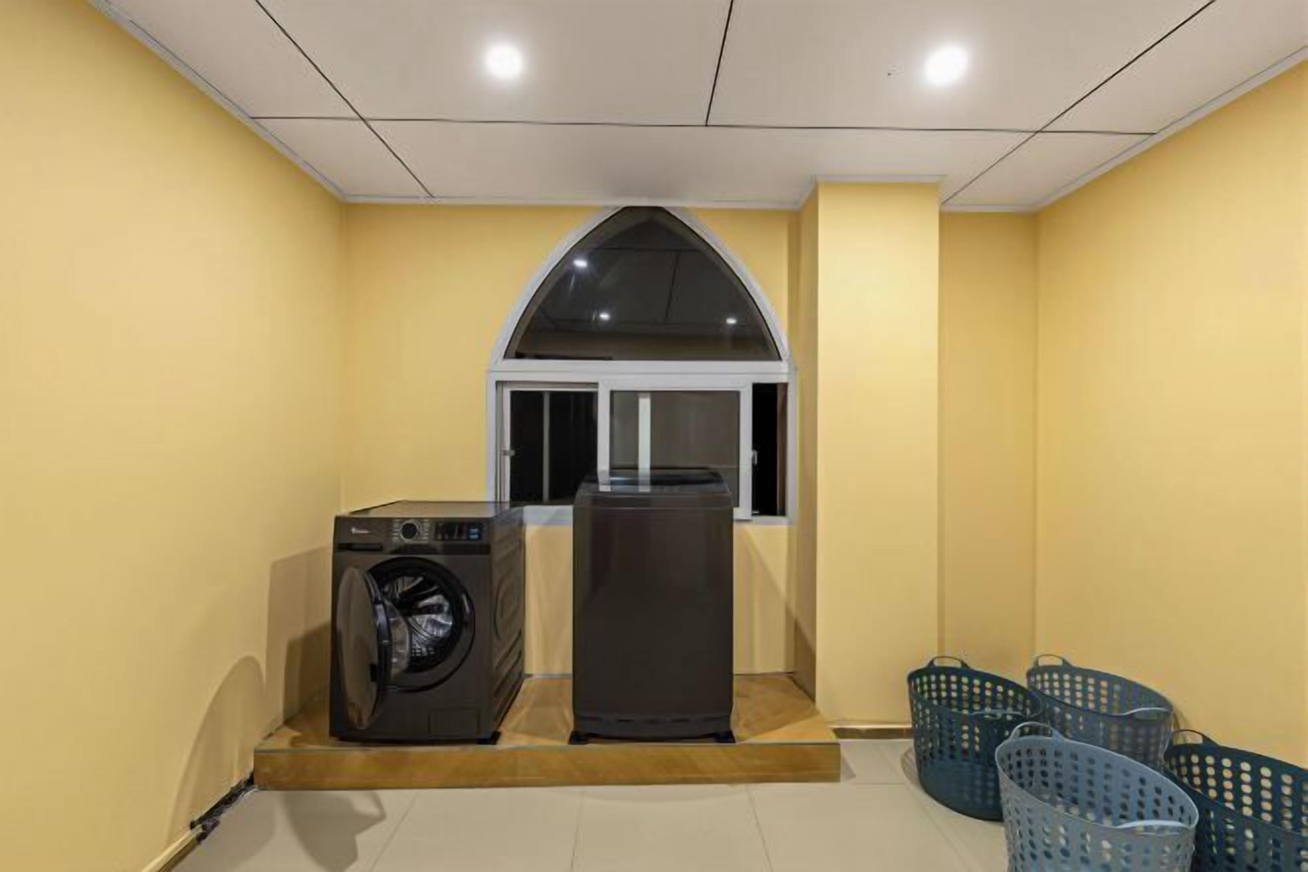 A laundry room with a washing machine, dryer, and several baskets.