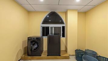 A laundry room with a washing machine, dryer, and several baskets.