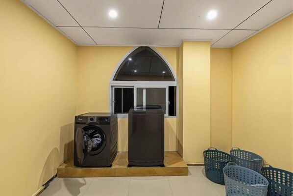 A laundry room with a washing machine, dryer, and several baskets. - Taimei Holiday Hotel (Chongqing)
