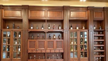 A large wooden wine cabinet with multiple shelves and glass doors, containing various bottles and glasses.