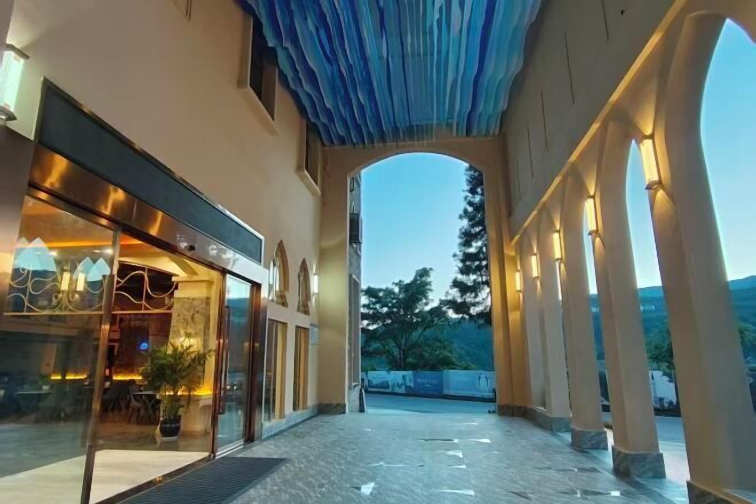 An indoor corridor with a glass storefront on the left and a covered walkway on the right.