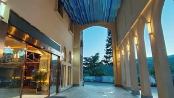 An indoor corridor with a glass storefront on the left and a covered walkway on the right.